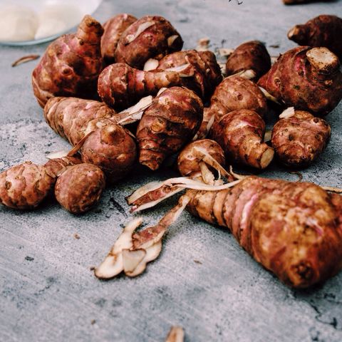 cropped hands peeling jerusalem artichoke